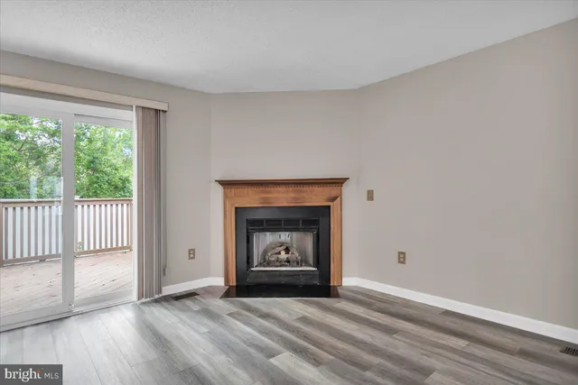 an empty room with wooden floor fireplace and windows