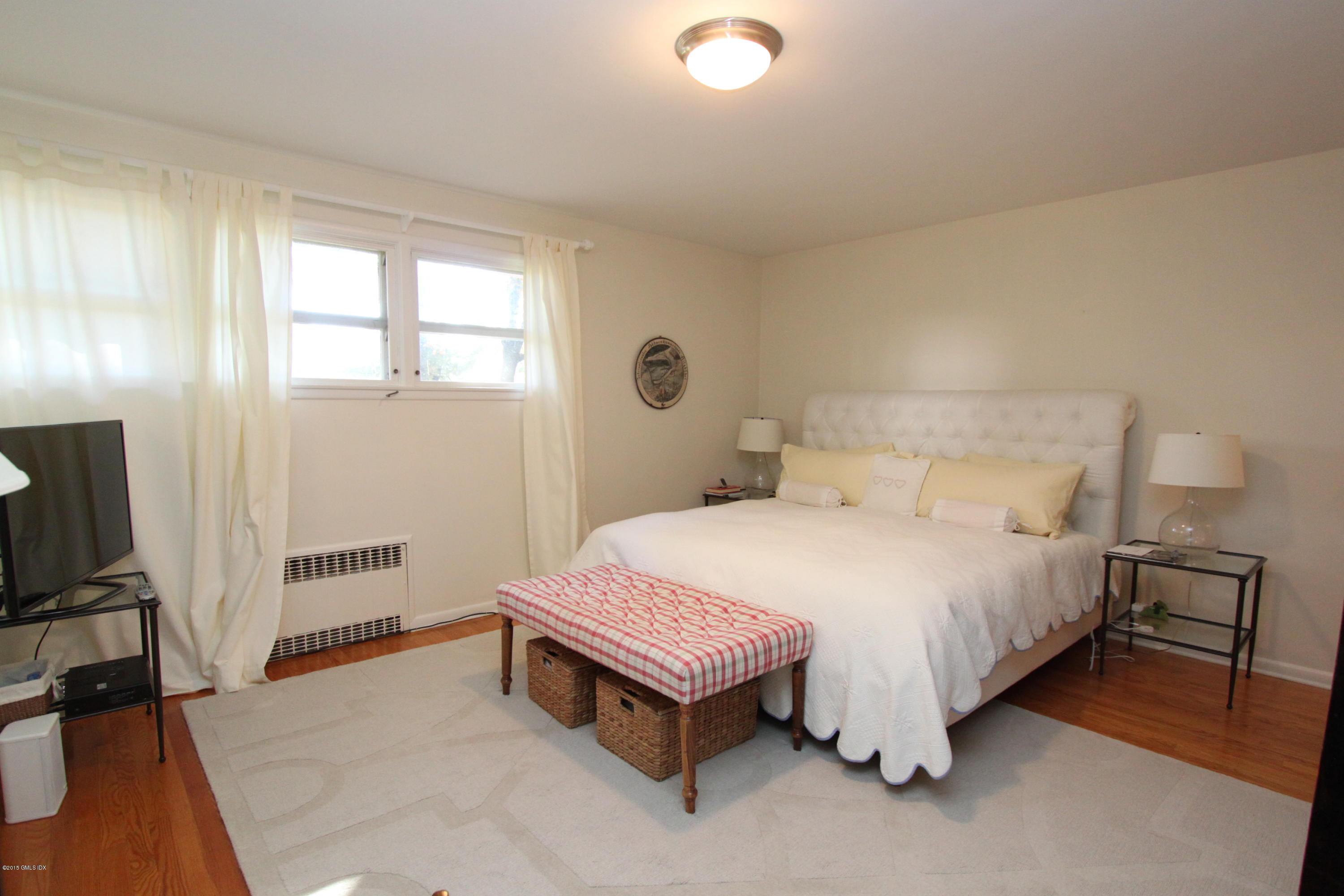 26 Beechcroft Road Greenwich, CT 06830 - Photo 5 of 6 a bedroom with a bed and a flat tv screen on a dresser