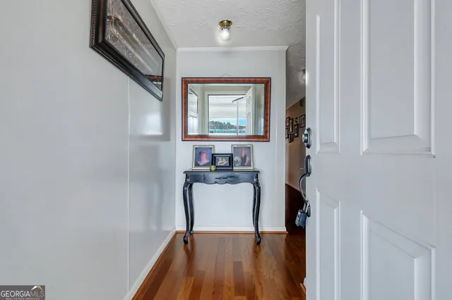 a view of a hallway with wooden floor and a bathroom