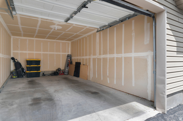 25 West Ridge Road, Unit 25 Saratoga Springs, UT 84045 - Photo 18 of 22 Interior garage featuring an open overhead door, concrete flooring, and unfinished walls