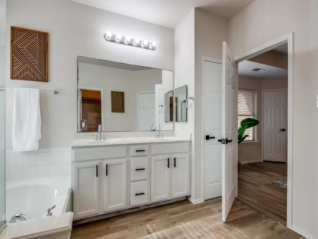 a spacious bathroom with a granite countertop sink mirror and a bathtub