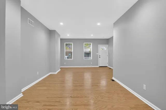 a view of a hallway with wooden floor and a bathroom