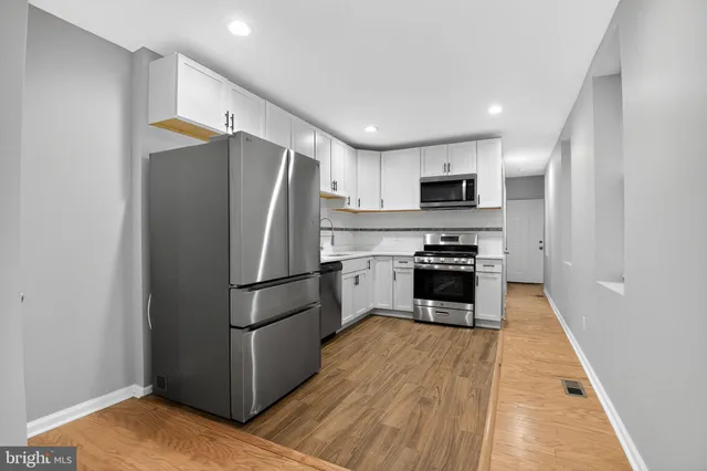 a kitchen with a refrigerator a stove top oven and cabinets