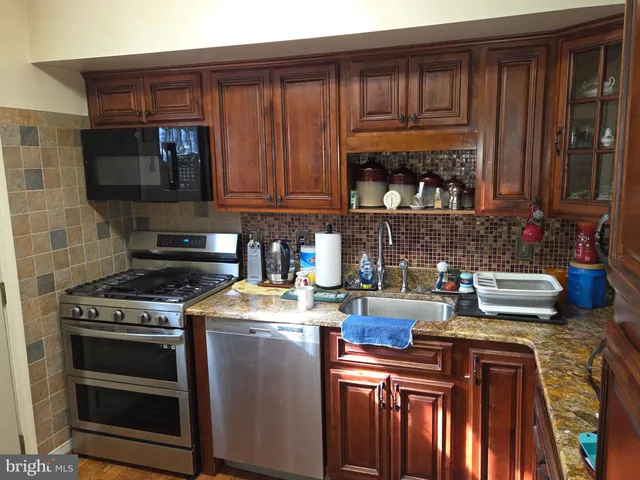 a kitchen with granite countertop a stove top oven a sink dishwasher and cabinets with wooden floor