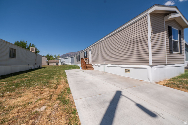 2491 Highway 89, Unit 403 Pleasant View, UT 84404 - Photo 27 of 32 Beige vinyl siding with white trim, a single window with black shutters, and an entry door with wooden steps