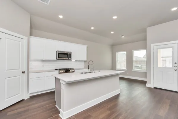 a kitchen with a sink stove and wooden floor