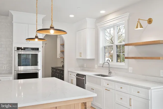 a kitchen with stainless steel appliances a stove a sink a refrigerator and windows