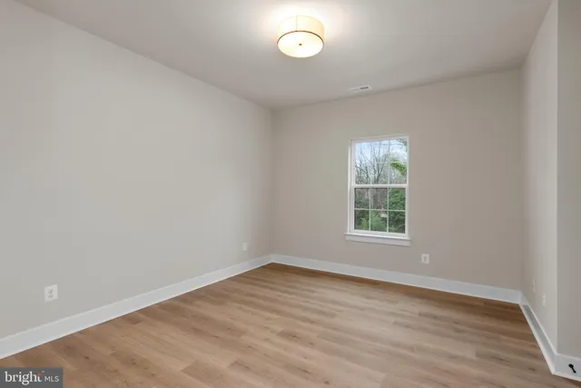 an empty room with wooden floor and a window