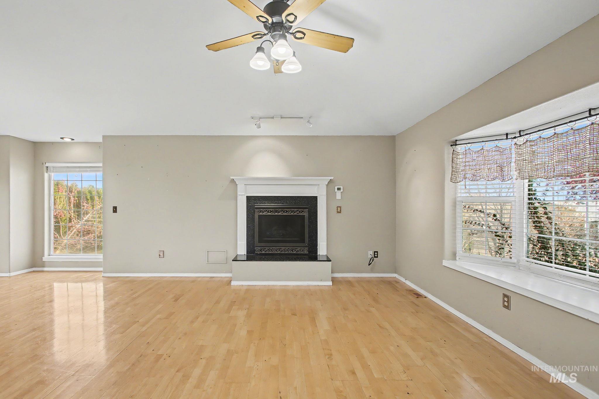 2242 Chukar Lane Clarkston, WA 99403 - Photo 10 of 41 Unfurnished living room with a fireplace with raised hearth, track lighting, light wood-type flooring, and ceiling fan