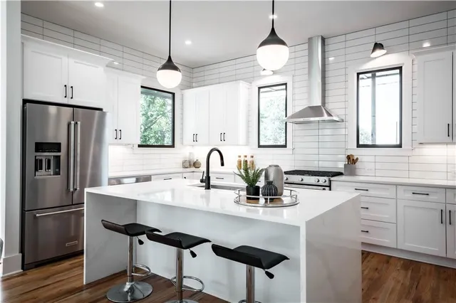 a kitchen with granite countertop a sink cabinets stainless steel appliances and windows