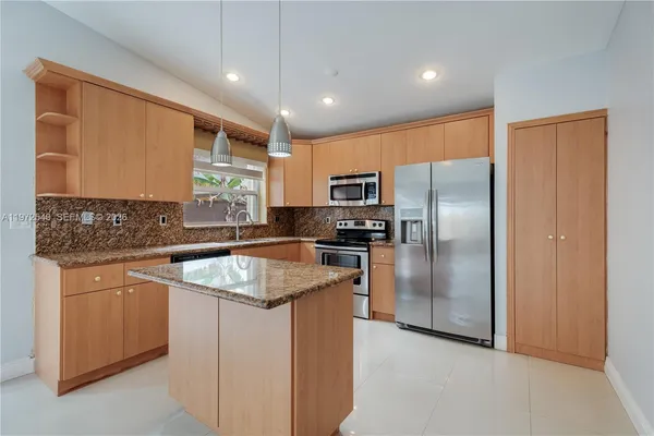 a kitchen with granite countertop stainless steel appliances a refrigerator a sink a stove a microwave a counter top and cabinets