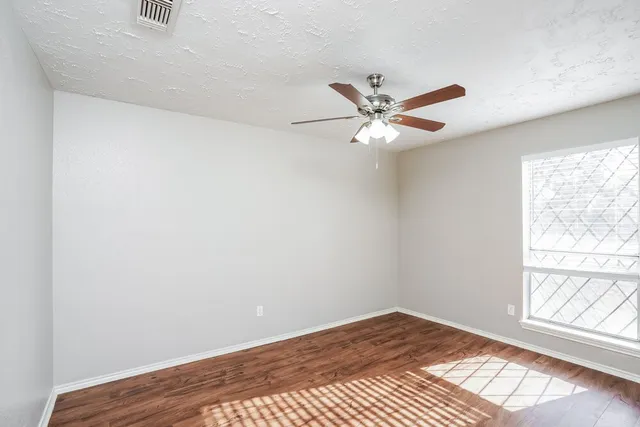 an empty room with a window and a fan