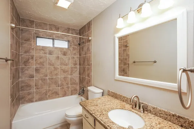 a bathroom with a granite countertop sink toilet and shower