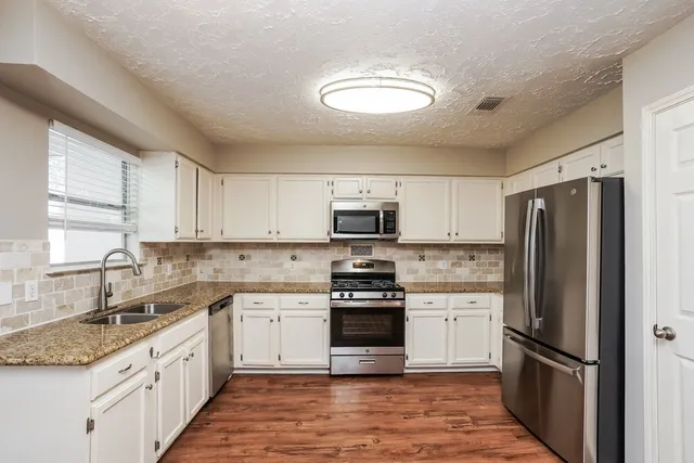 a kitchen with stainless steel appliances granite countertop a refrigerator stove a sink and dishwasher