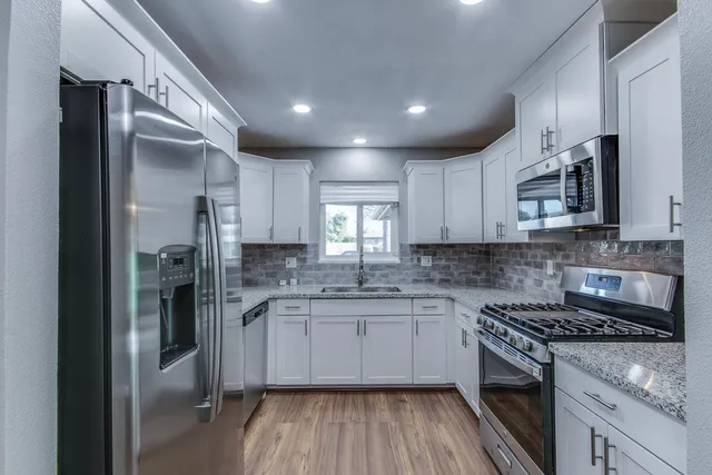 a kitchen with stainless steel appliances granite countertop a sink stove and refrigerator