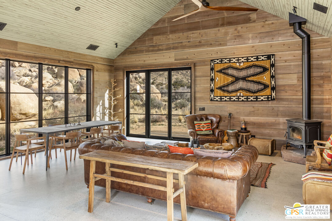 1653 Roadrunner Rut Pioneertown, CA 92268 - Photo 24 of 60 a living room with furniture a flat screen tv and a floor to ceiling window