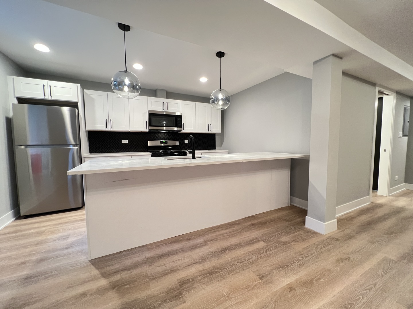 911 South Miller Street, Unit G Chicago, IL 60607 - Photo 3 of 11 a kitchen with kitchen island a white counter top space cabinets and stainless steel appliances