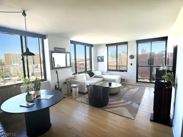 a living room with large couches bookshelf and a dining table with wooden floor