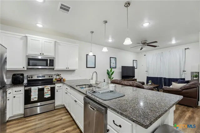 a kitchen with stainless steel appliances granite countertop a sink stove and refrigerator