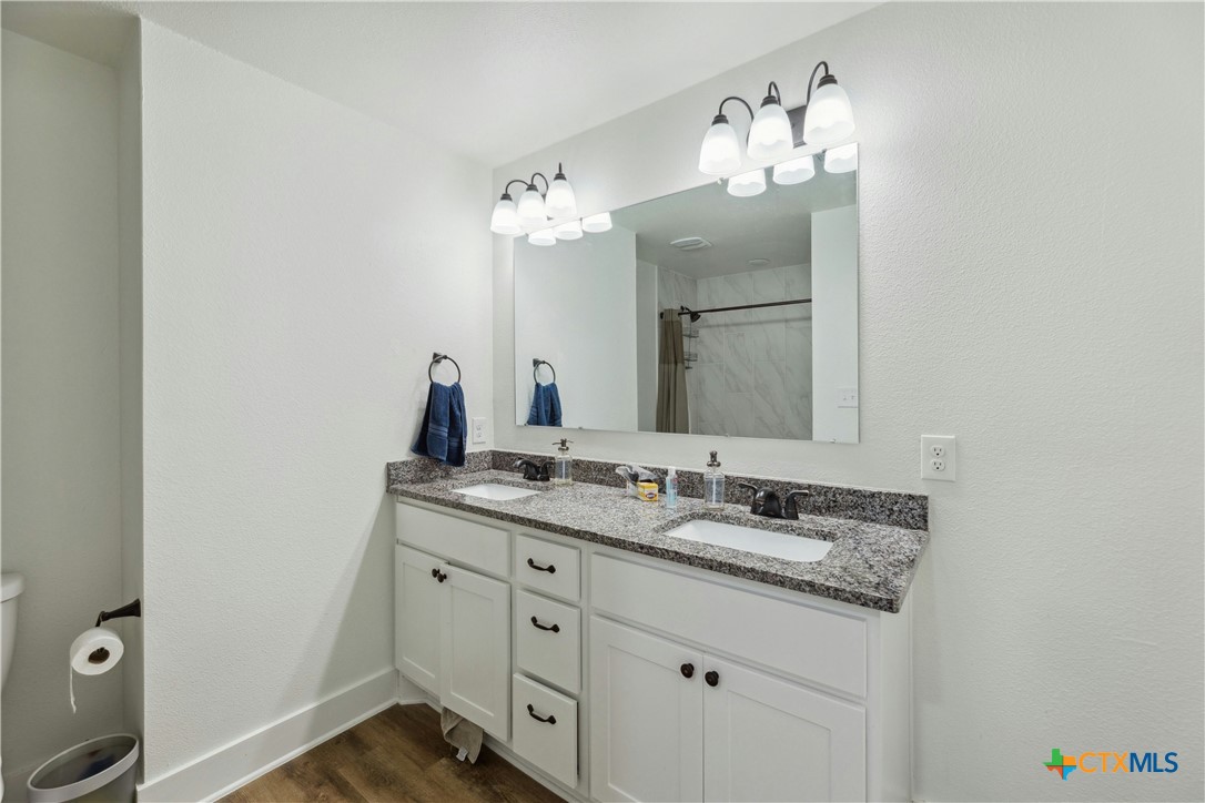 1952 Royal Loop Belton, TX 76513 - Photo 12 of 14 a bathroom with a granite countertop sink a large mirror and a toilet