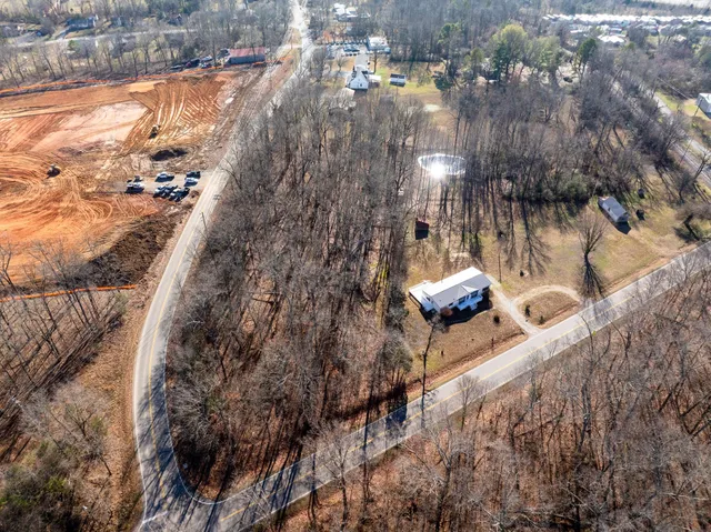 a backyard of a house with large trees and lawn chairs