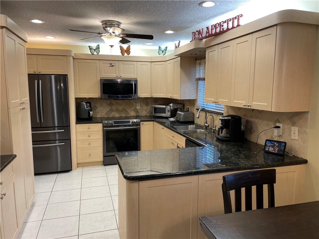 8581 Southwest 27th Place Davie, FL 33328 - Photo 6 of 10 a kitchen with stainless steel appliances granite countertop a stove a refrigerator a sink a microwave and island
