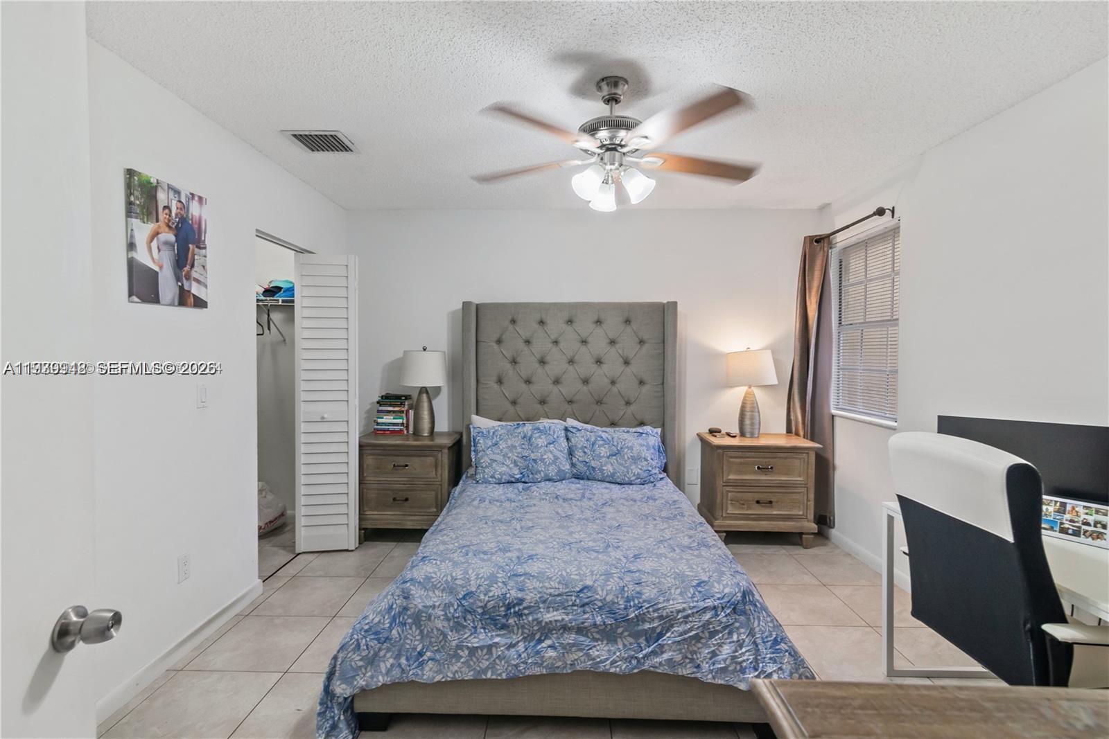 18348 Northwest 68th Avenue, Unit D Hialeah, FL 33015 - Photo 11 of 18 a bedroom with a large bed and a chandelier