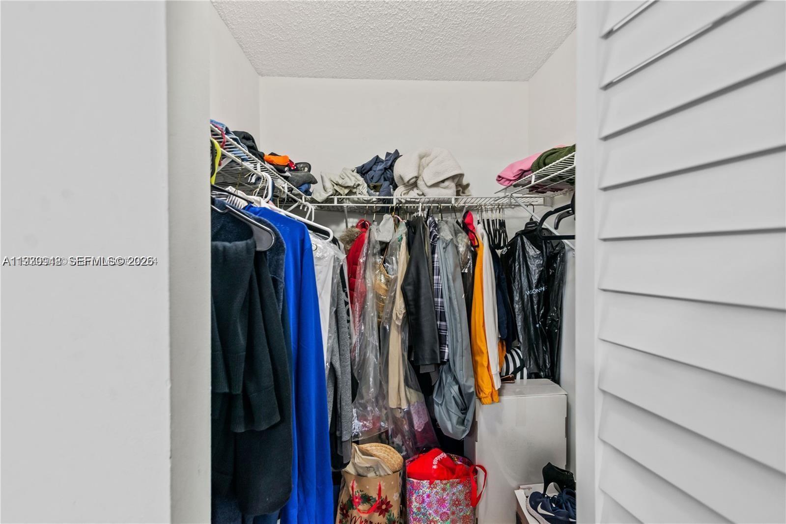 18348 Northwest 68th Avenue, Unit D Hialeah, FL 33015 - Photo 12 of 18 a view of walk in closet with clothes