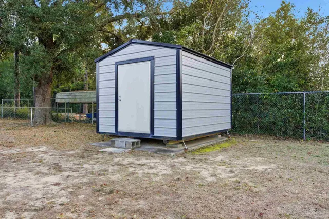 a backyard of a house with white wall and wooden fence