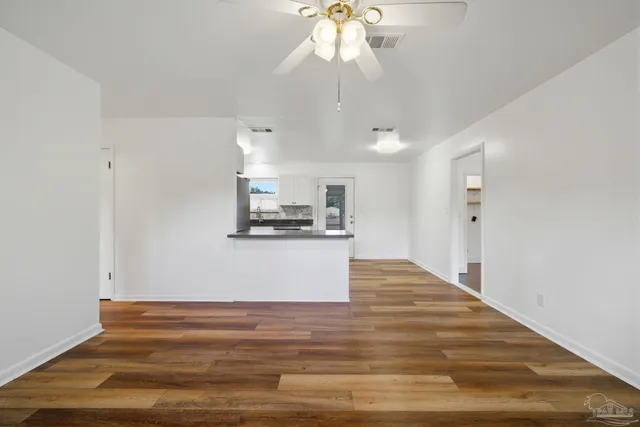 a view of kitchen and empty room with wooden floor