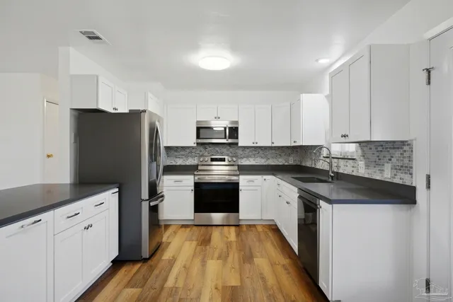 a kitchen with granite countertop white cabinets and stainless steel appliances