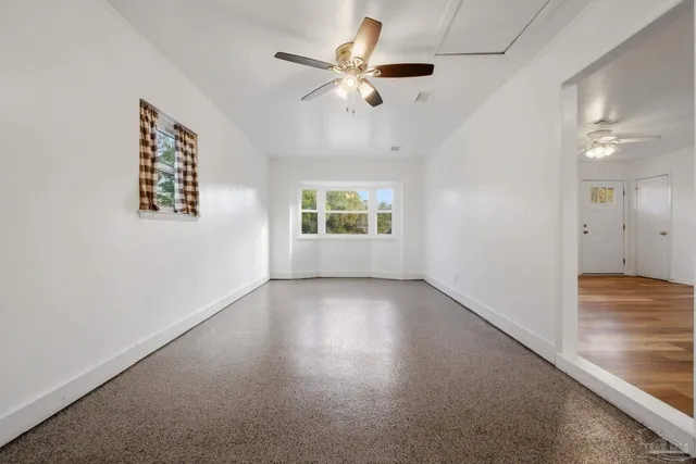 an empty room with a window and a ceiling fan