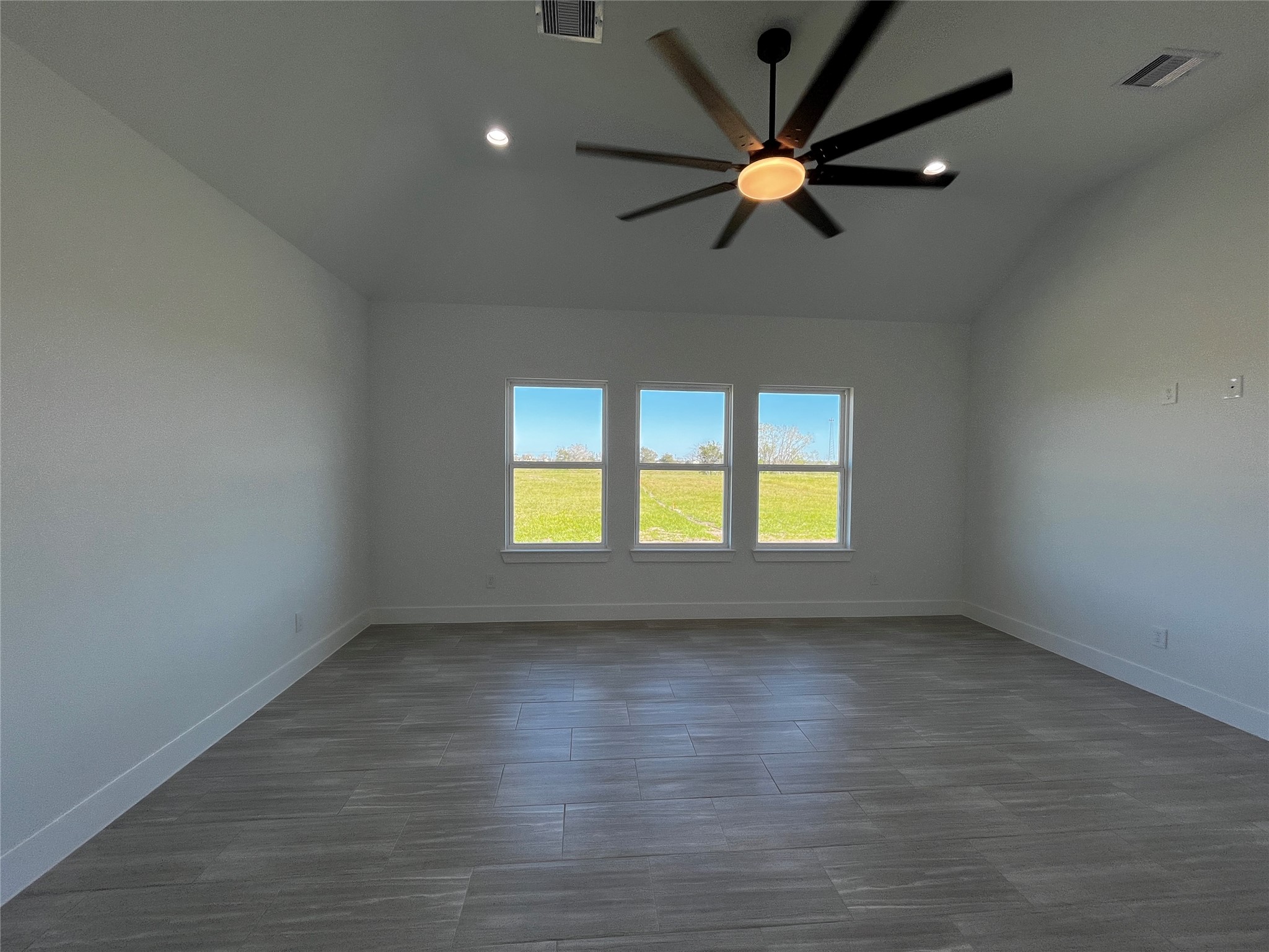 471 Buffalo Trail Angleton, TX 77515 - Photo 23 of 35 A spacious, modern room with large windows offering abundant natural light and a scenic outdoor view. The room features sleek flooring, white walls, and a stylish ceiling fan.