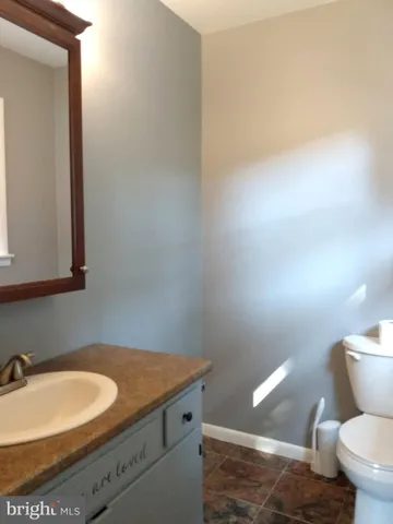 a bathroom with a granite countertop toilet and a sink