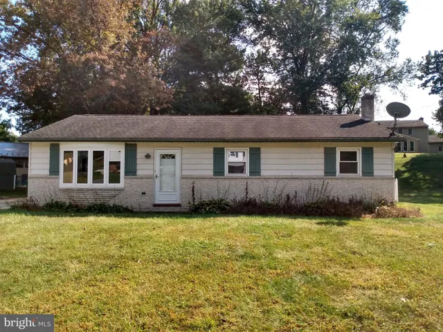 a view of a house with a yard and a large tree