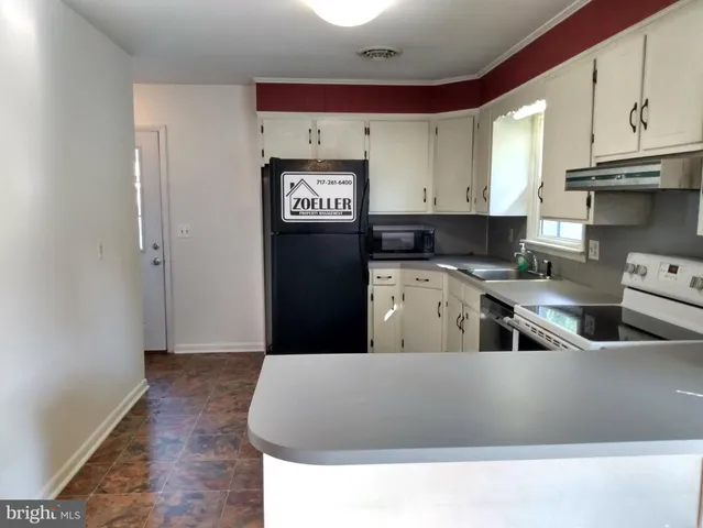 a kitchen with stainless steel appliances granite countertop a refrigerator a sink a stove and wooden cabinets