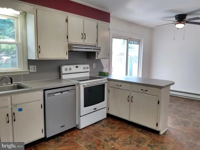 a kitchen with stainless steel appliances granite countertop a sink a stove and white cabinets with wooden floor