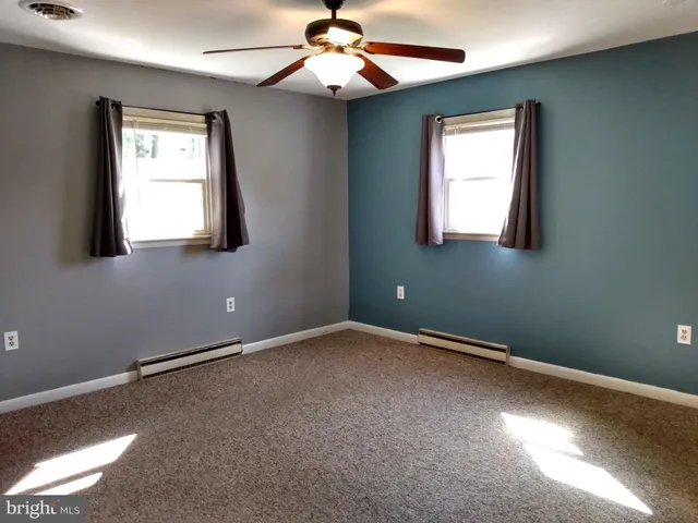 an empty room with a window and a chandelier fan