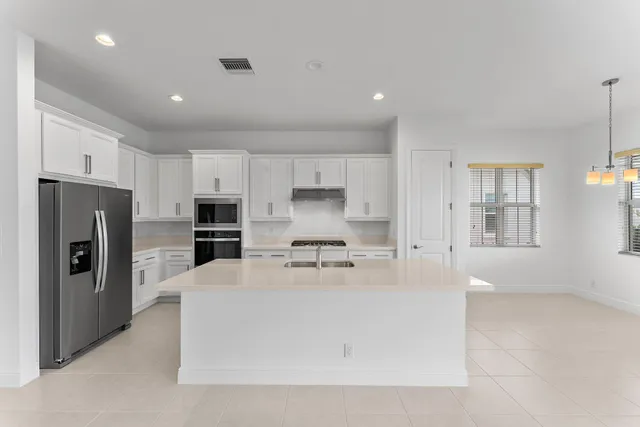 a view of large kitchen with granite countertop lots of counter top and stainless steel appliances