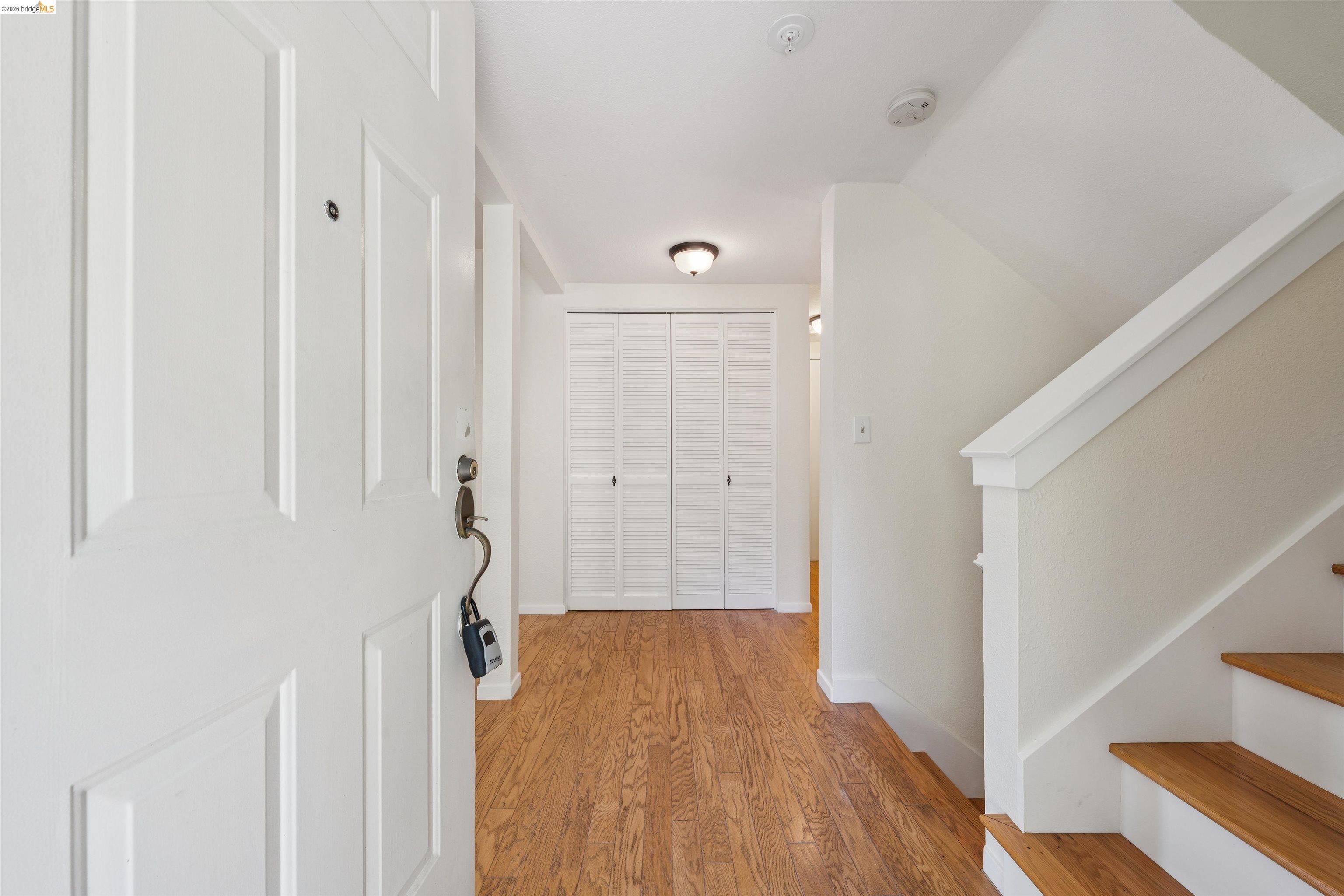 261 Redhawk Road Novato, CA 94949 - Photo 10 of 44 Entry foyer featuring wood-finish flooring, a white paneled entry door, and a staircase with wood treads