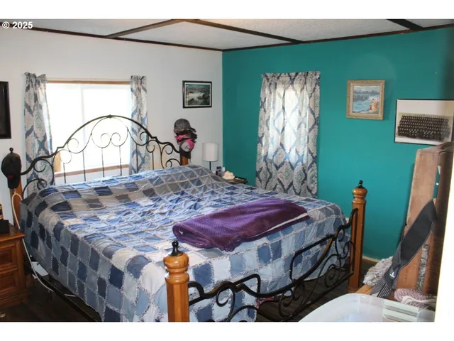 a bed sitting in a bedroom next to a window and a flat screen tv