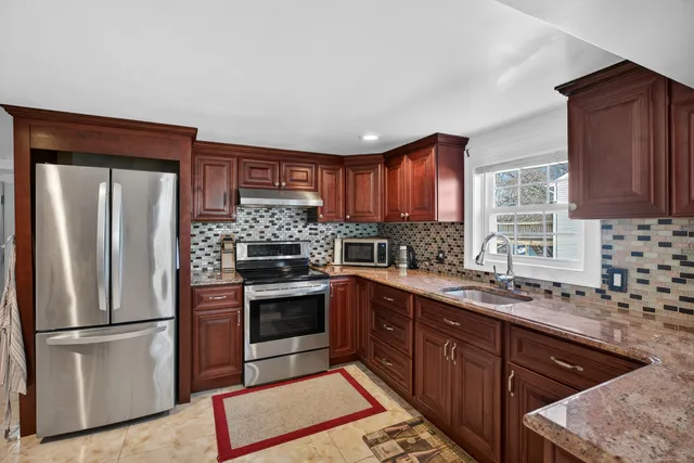 a kitchen with granite countertop stainless steel appliances a sink cabinets and a window