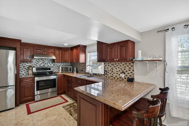 a kitchen with granite countertop stainless steel appliances a stove a sink island and a refrigerator