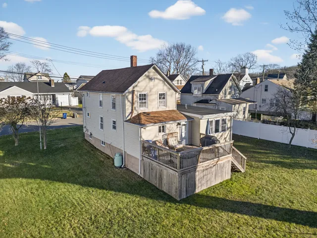 a view of a big house with a big yard potted plants and large tree