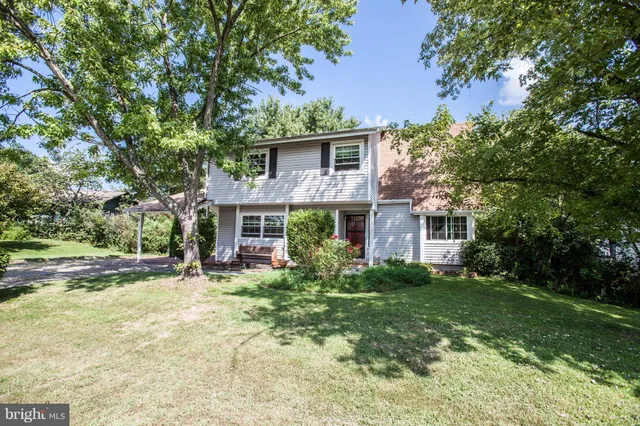 a view of house with yard and trees in the background