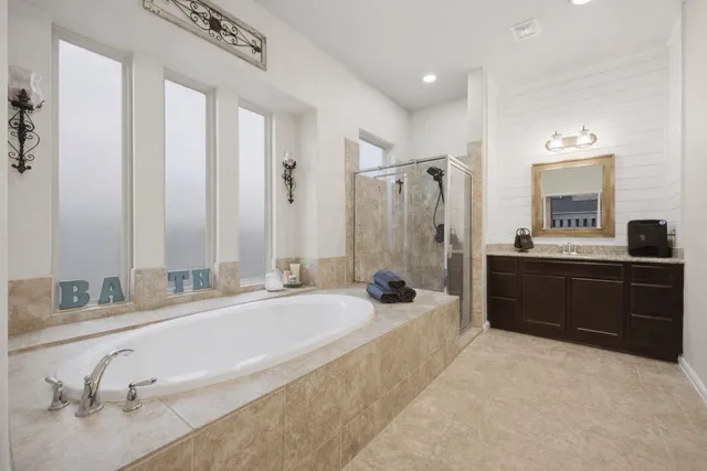 a spacious bathroom with a tub sink and mirror