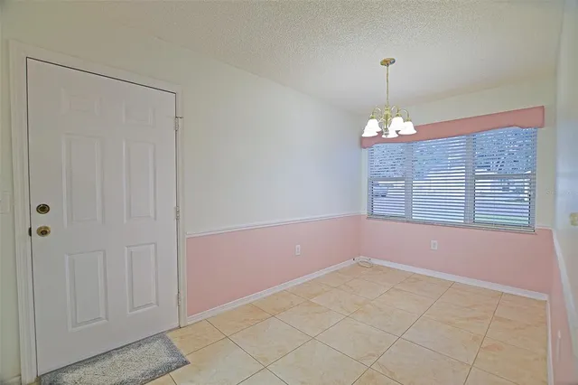 a view of an empty room and chandelier fan