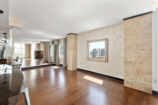 a view of an empty room with wooden floor and a window