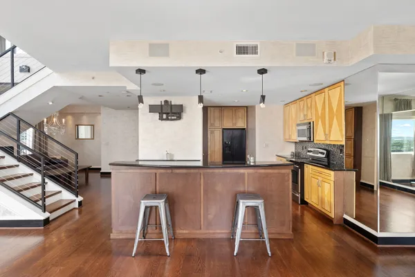 a kitchen with stainless steel appliances granite countertop a table chairs refrigerator and sink
