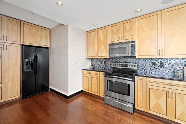 a kitchen with granite countertop white cabinets stainless steel appliances and a window